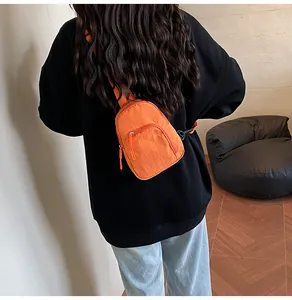Détail macro du sac de poitrine en nylon orange vif avec sangle réglable et fermeture éclair