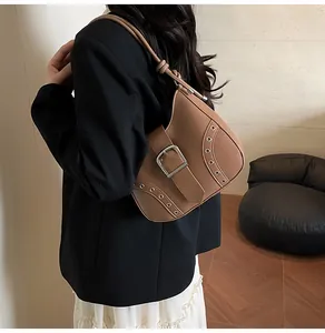 Brown retro shoulder bag detail featuring large buckle and metal eyelet decorations