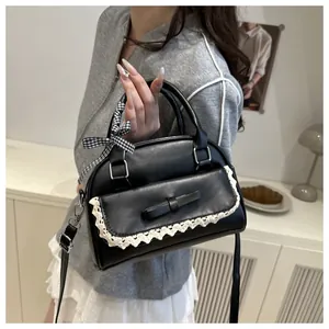 Close-up of black PU leather bag featuring lace trim, bow pocket and checkered ribbon handle