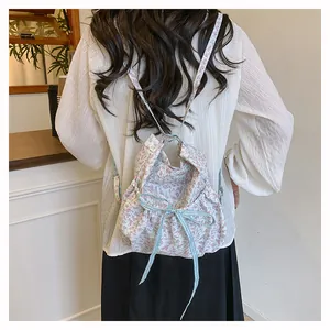 Rear view of a floral drawstring backpack with blue plaid bow on a female model