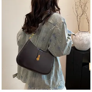 Detail of a vintage dark brown hobo bag with a retro gold oval clasp on a denim jacket