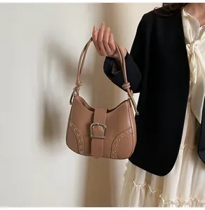 Detailed view of brown PU leather shoulder bag with metallic buckle and eyelet accents