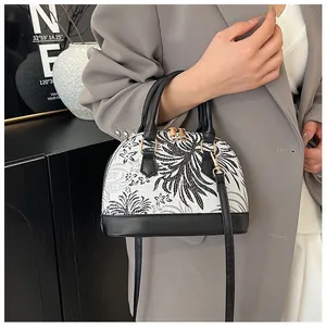 Detail of a chic shell bag featuring black floral prints and premium gold hardware