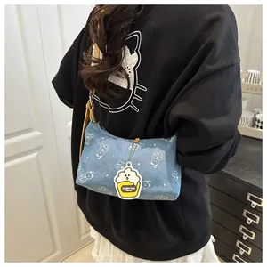 Blaue Denim-Umhängetasche mit weißem Bärenprint und gelbem Cupcake-Anhänger im Detail