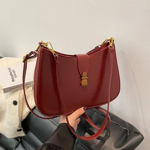 Vintage burgundy half-moon shoulder bag with retro gold buckle in a commute style scene