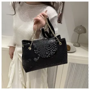 Close-up of black snake pattern texture and gold chain on stylish large tote bag