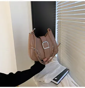 Detail of hobo bag featuring silver buckle and metal eyelets on brown leather surface