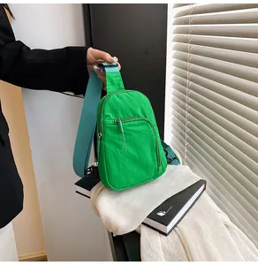 Détail du sac bandoulière en nylon vert plissé avec deux compartiments zippés et sangle bleue
