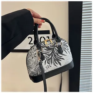 Detail view of monochrome shell bag with leaf patterns and elegant black leather trim