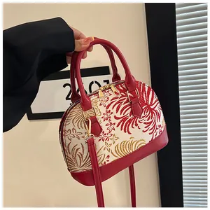 Detailed macro view of red and gold floral embroidery on shell handbag with metal zippers
