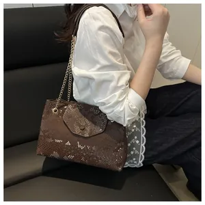 Brown snakeskin textured tote bag with golden metal chain strap shown on a model