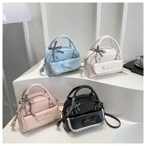 Detail view of four colorful PU leather crossbody bags with lace trim and bow decorations