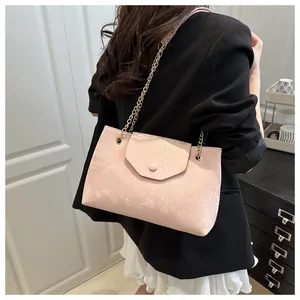 Detail of pink croc-embossed tote bag featuring a gold chain strap and round buckle