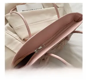 Detailed close-up of the smooth silver zipper and floral applique on pink shoulder bag