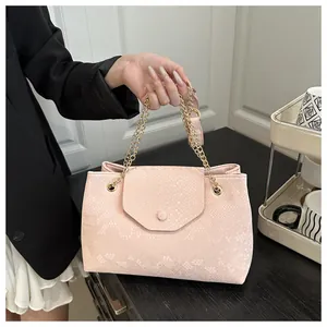 Detail of pink snake-embossed tote bag featuring elegant gold chain strap and texture
