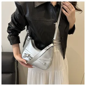Sac demi-lune argenté avec détail nœud porté par un mannequin pour l'ajustement