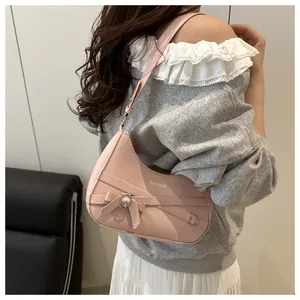 Détail du sac demi-lune rose en cuir PU avec logo argenté et décoration de nœud