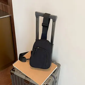 Bolso bandolera minimalista de nailon negro sobre una maleta para uso en viajes
