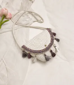 Detail of bohemian straw bag featuring purple floral embroidery and tiered colored tassels