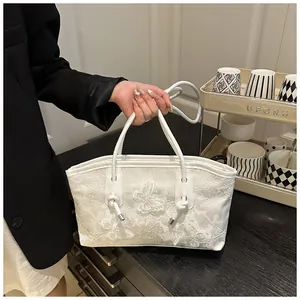 Detailed close-up of white lace embroidery with 3D floral and butterfly patterns on bag