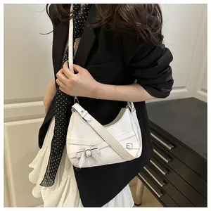 Détail du sac blanc en demi-lune avec lanières croisées et boucle en forme de nœud