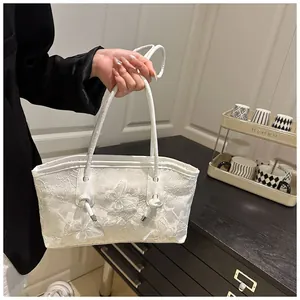 Detail of white tote bag with floral lace embroidery and slim leather handles