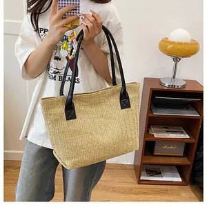Detail of V-shaped raffia weave texture and black leather handles on a summer bucket bag