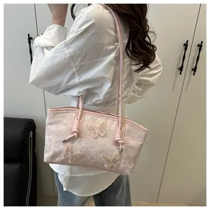 Detail view of a pink lace tote bag with three-dimensional butterfly embroidery on fabric