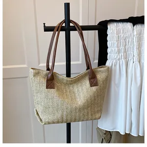 Close-up of woven straw tote bag featuring brown leather shoulder straps and beige texture