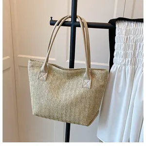 Close-up of woven straw tote bag featuring detailed V-shape knit and beige leather straps