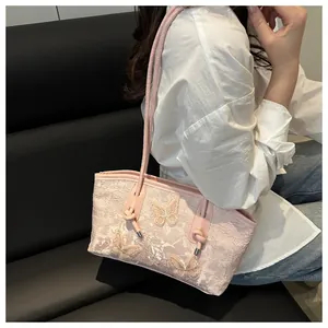 Detailed embroidery of floral and butterfly patterns on a pink tote bag