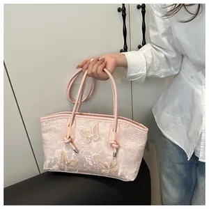 Detail of pink lace tote bag featuring three 3D butterfly appliqués and a long strap