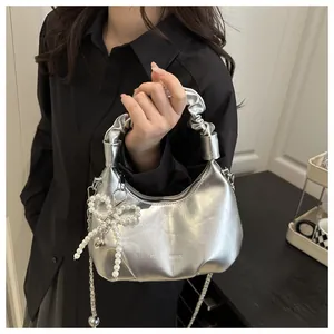 Detail of silver metallic textured bag featuring pearl bow and fashion logo engraving