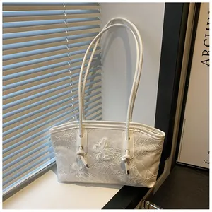 Close-up of elegant white tote with butterfly embroidery and delicate lace texture