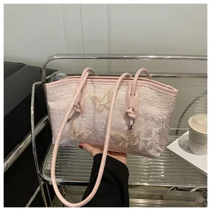 Detail of light pink lace tote bag with 3D butterfly embroidery and slim handles
