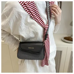 Detail of crossbody bag featuring black leather flap with gold lettering and woven texture