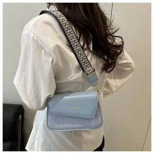 Side view of light blue leather crossbody bag with ethnic style woven strap on a model