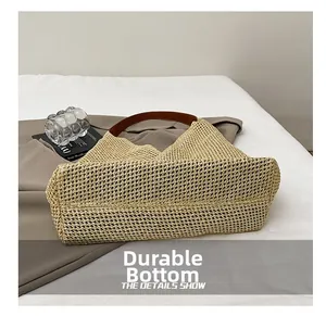 Detail view of the durable flat bottom on a beige woven tote bag with leather handles