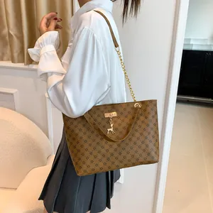 Large brown tote bag with geometric patterns, gold chain strap, and deer pendant for women