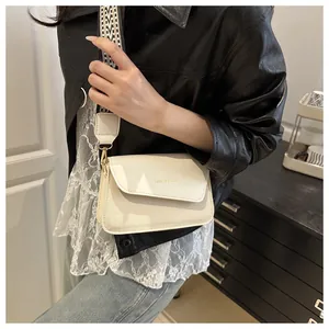 Detail of off-white square crossbody bag with textured fabric and wide geometric strap