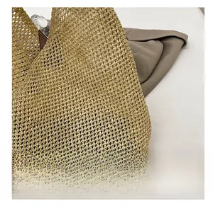 Detail of hand-woven straw shoulder bag showing textured mesh weave and leather strap