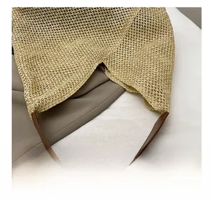 Detail showing the sturdy faux leather handle stitched to the woven straw summer tote bag