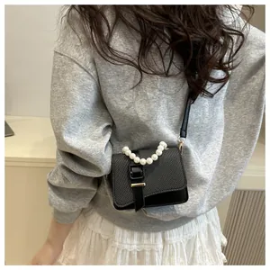 Detail of black crossbody square bag with pearl handle and woven texture on model