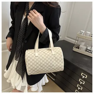 Modèle portant un sac Boston vintage crème avec motif M et doubles anses supérieures