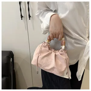 Detalle del bolso con cordón rosa claro con asa de cuentas y textura satinada elegante