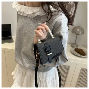 Detail of grey textured woven crossbody bag with pearl handle and metal buckle closure