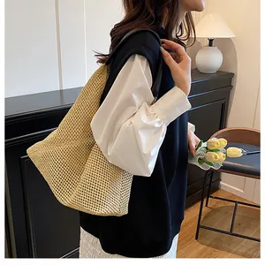 Spacious hollow-woven straw tote bag with brown straps shown on shoulder