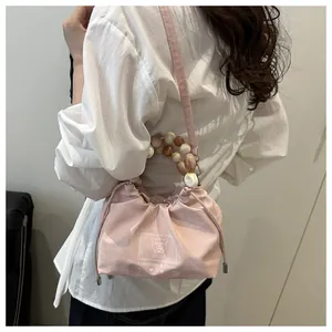 Detalle de bolso rosa con asa de cuentas jaspeadas y cierre de cordón ajustable