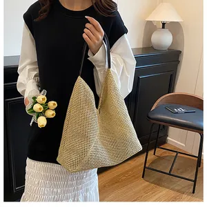 Detail of hand-woven straw tote bag featuring tight texture and dark leather shoulder straps