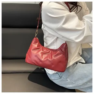 Dettaglio della trama goffrata rosso scuro e fibbia in metallo dorato sulla borsa a spalla